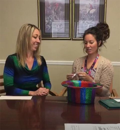 Two women are sitting at a table with a top hat on it