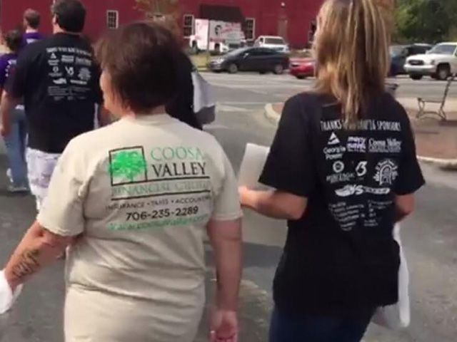 Two women wearing cook valley shirts are walking down a street
