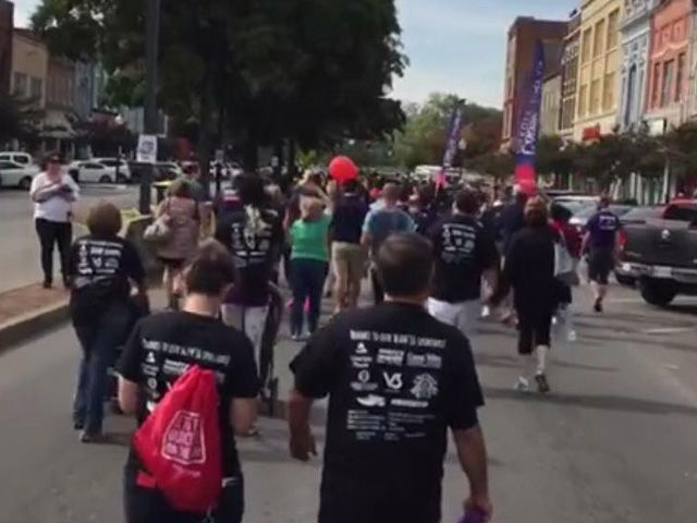 A group of people walking down a street wearing black shirts that say ' i love you ' on them
