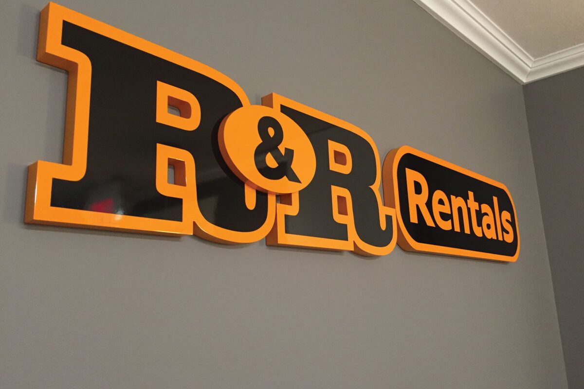 Illuminated dimensional sign for R&R Rentals with orange and black letters