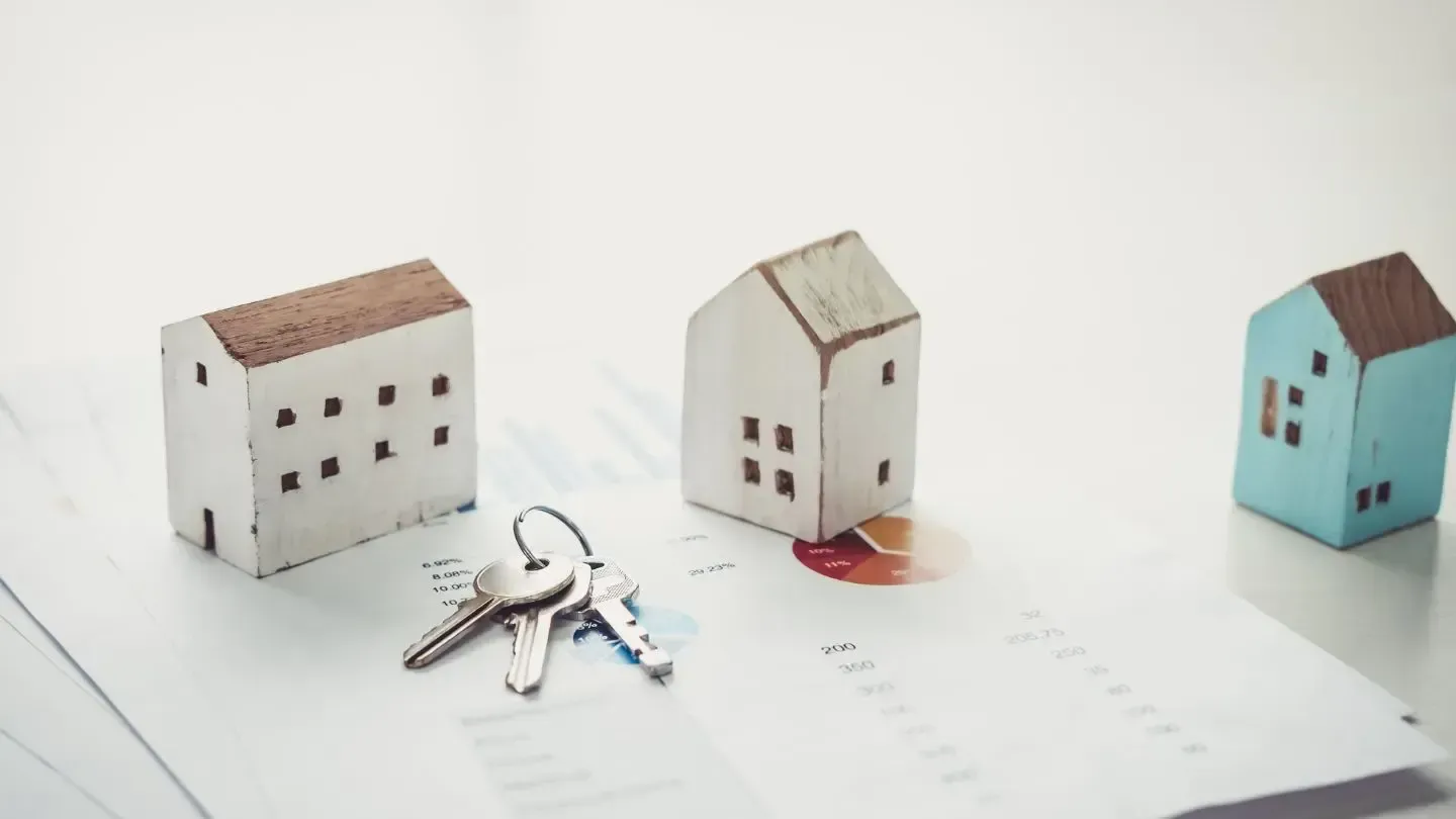 Three small houses and keys on a piece of paper.