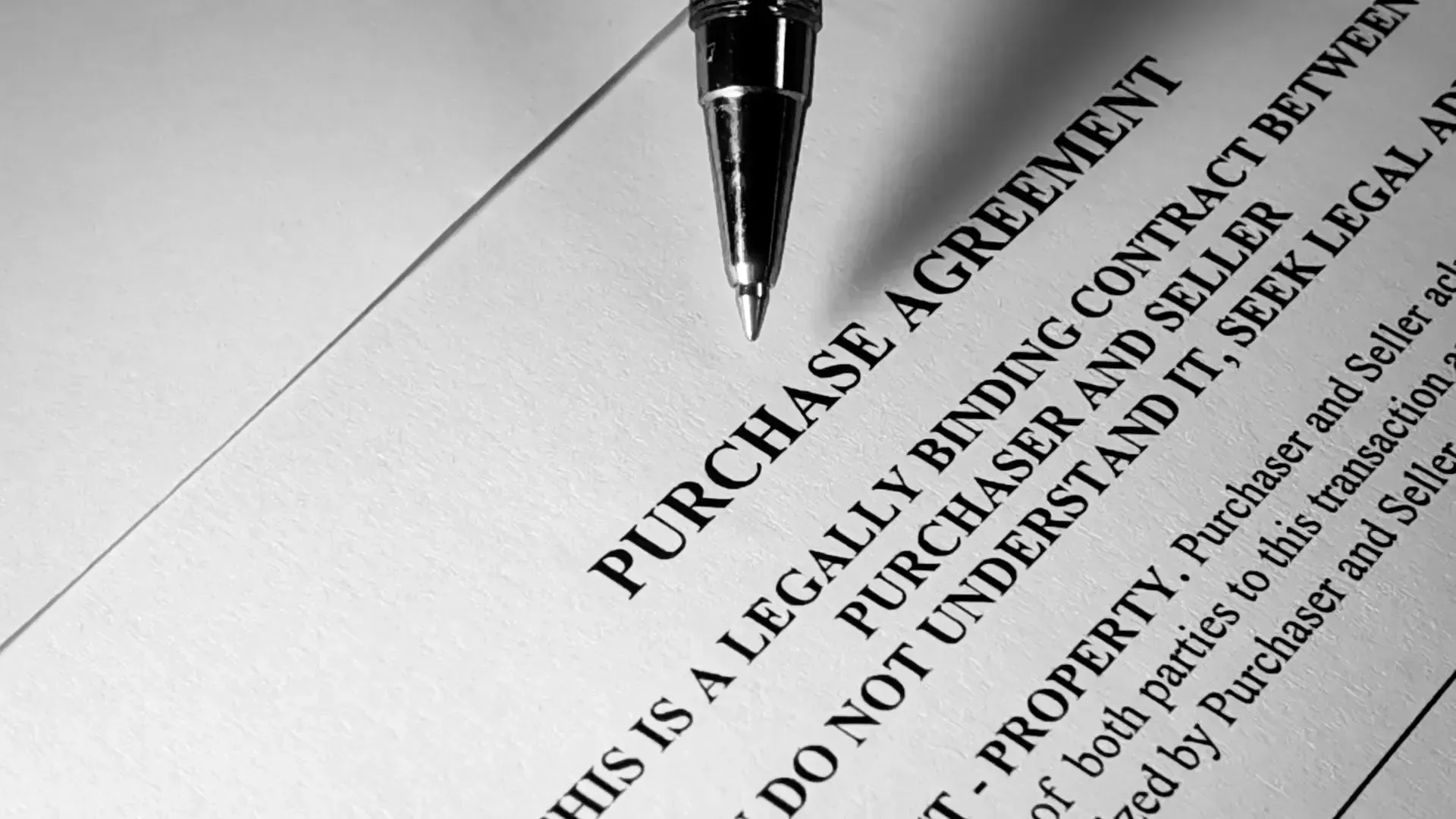 A pen is laying on top of a purchase agreement