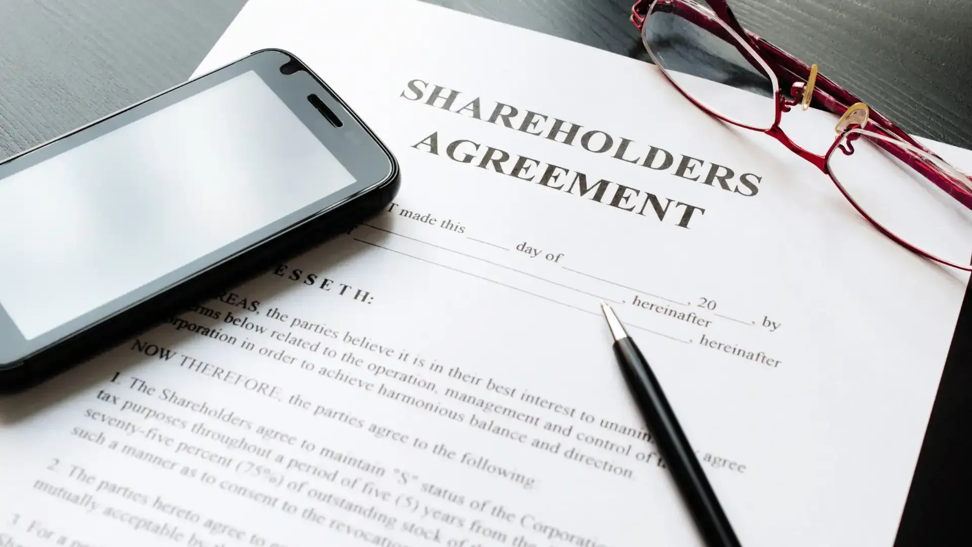 A shareholders agreement with a cell phone and glasses on it