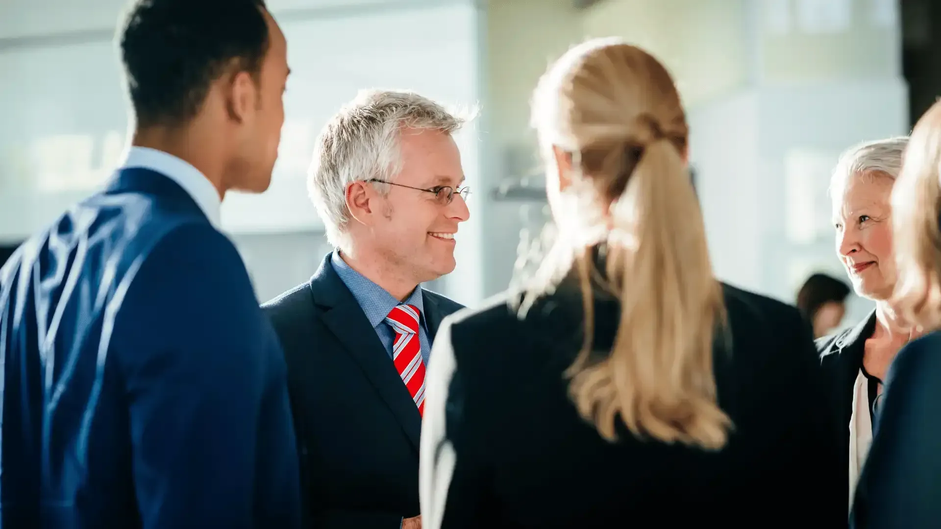 A group of business people are standing around talking to each other.