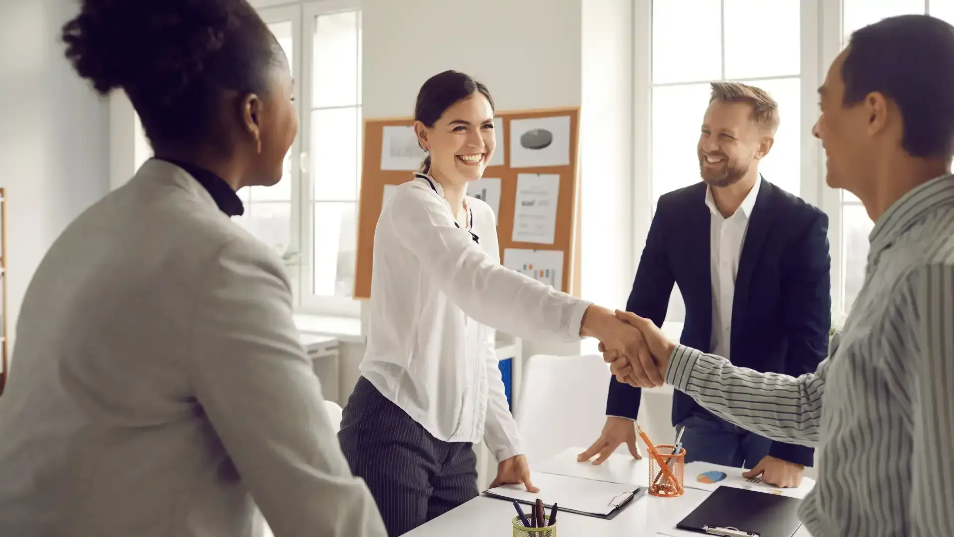 A group of people are shaking hands while sitting around a table.