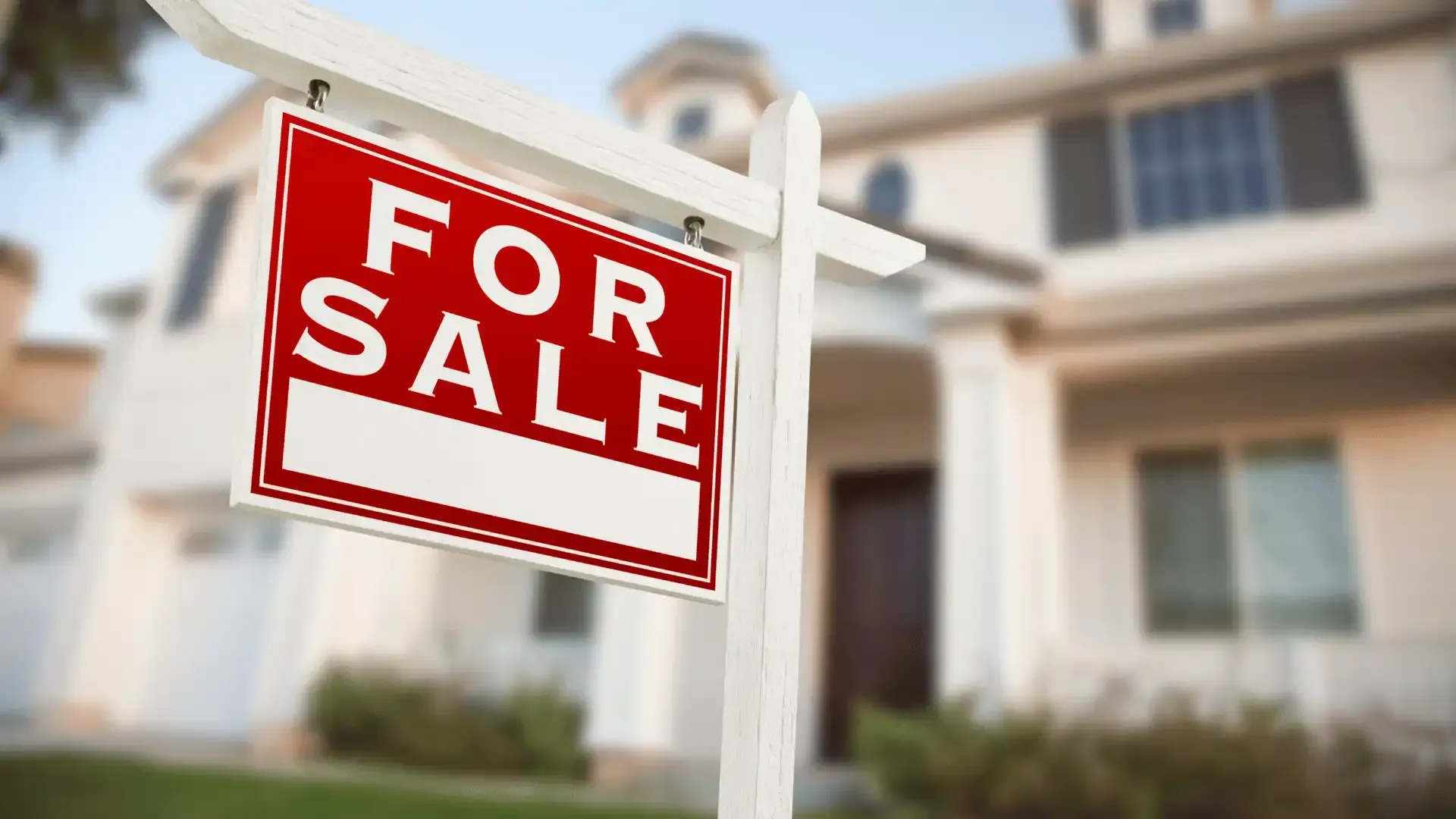 A for sale sign is hanging in front of a house.
