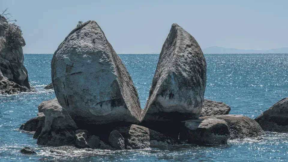 A large rock is sitting in the middle of the ocean.