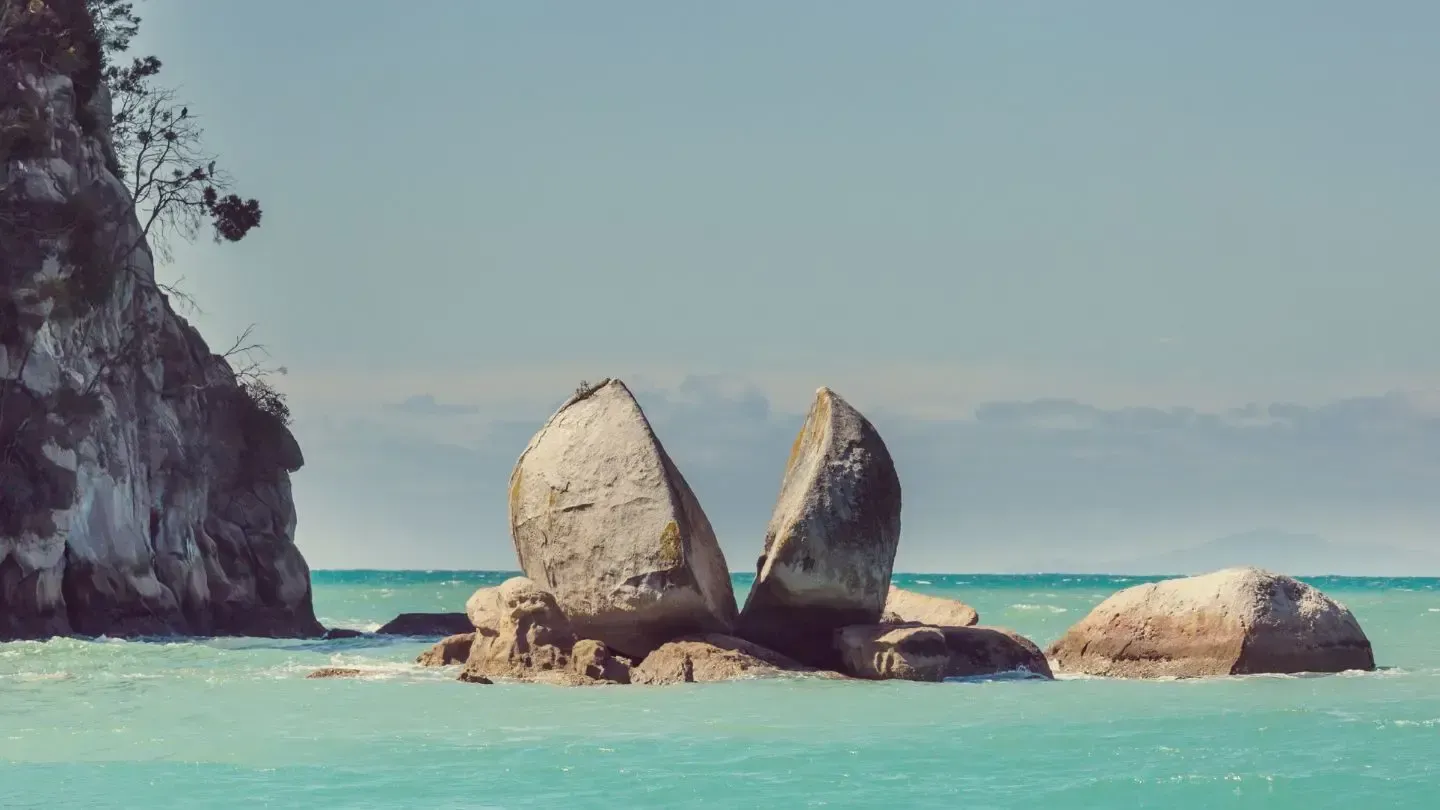 Split Apple Rock in Abel Tasman National Park, New Zealand; turquoise water, clear sky.