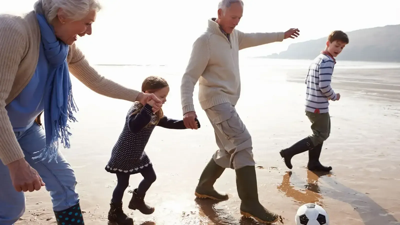 A family is playing with a soccer ball on the beach.