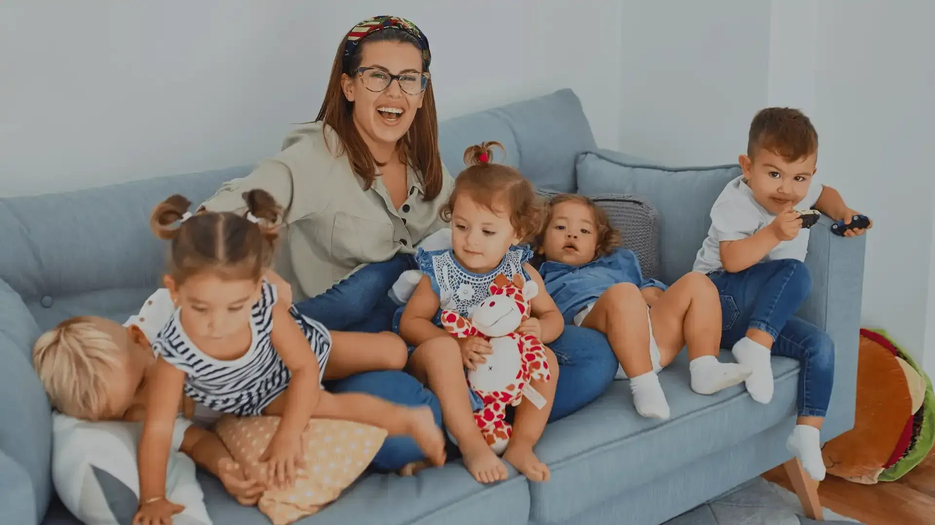 A woman is sitting on a couch with three children.