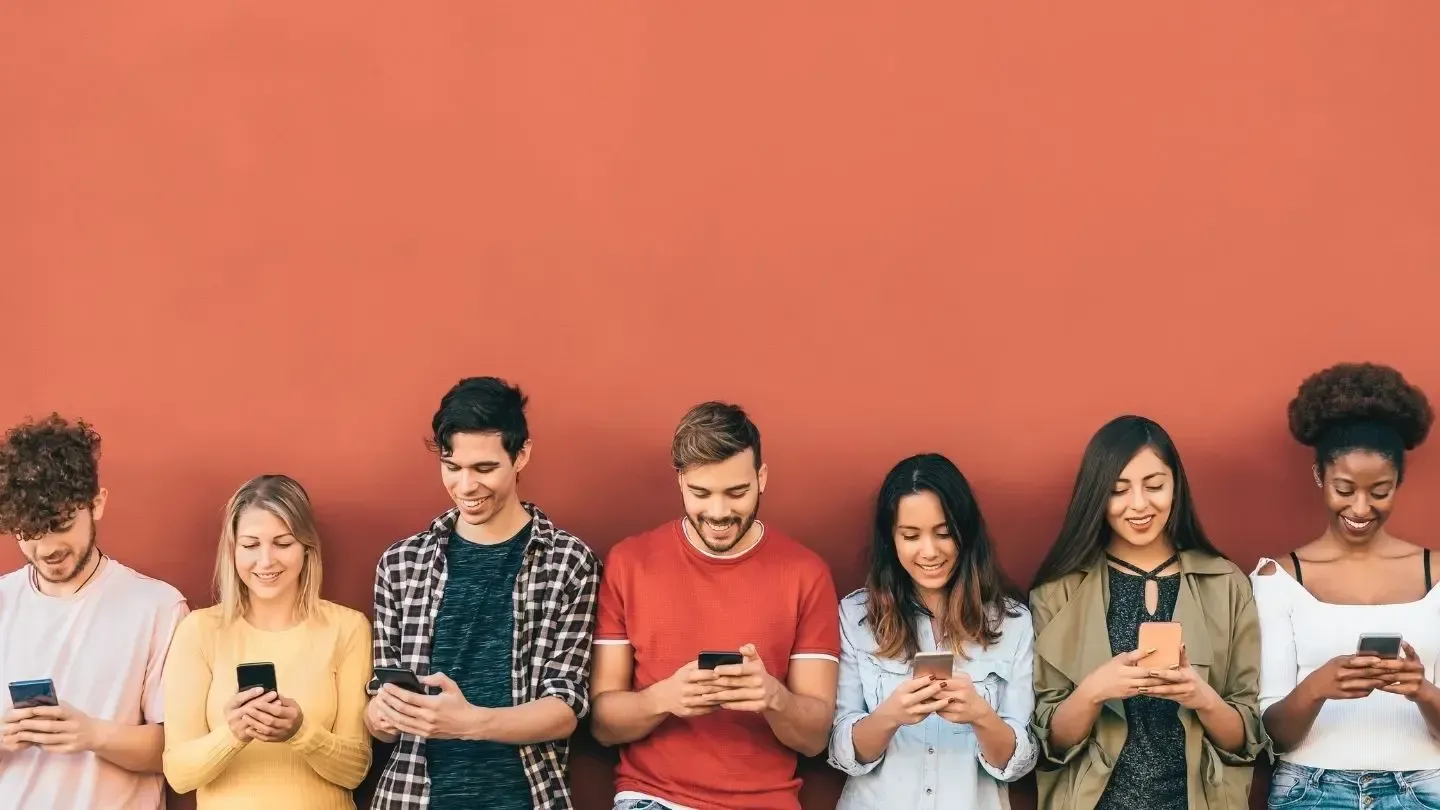 People using smartphones against a coral-colored wall.