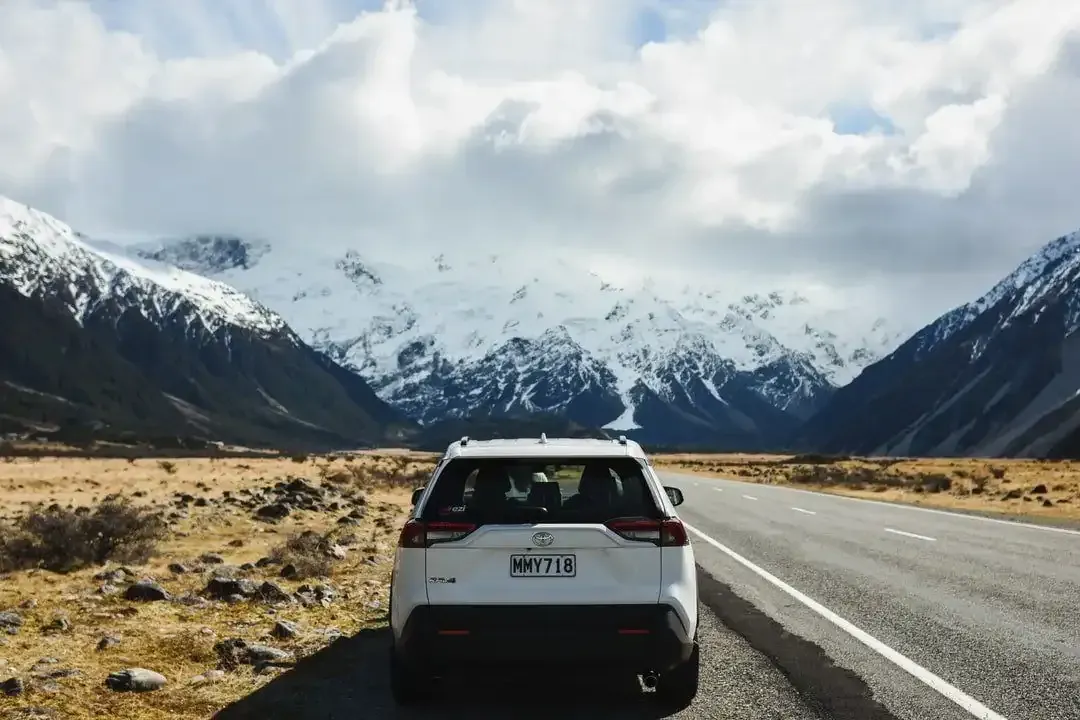a white car is parked on the side of a mountain road .
