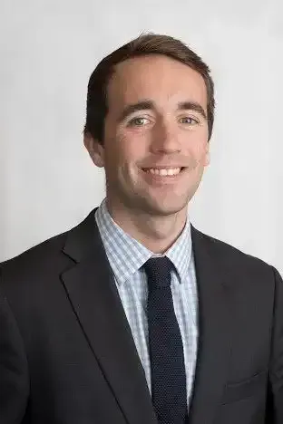 Ryan O'Connor in a suit and tie is smiling for the camera .