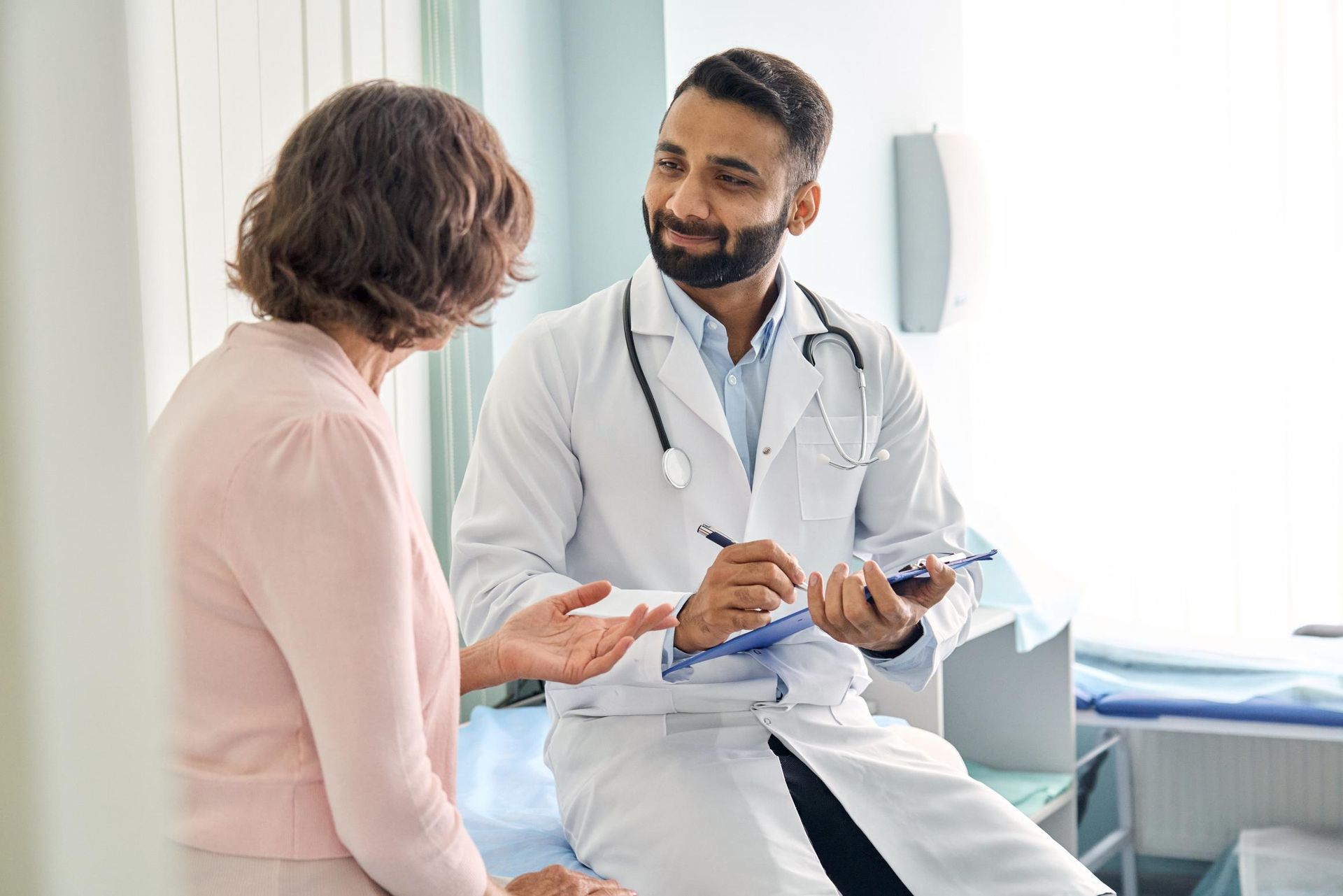 A doctor is holding a model of teeth and talking to a patient.