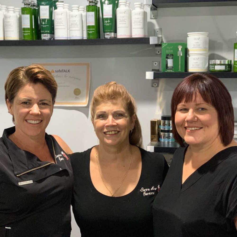 Three Women Are Posing For A Picture In Front Of A Shelf Full Of Beauty Products — Sarina Hair Fashions in Sarina, QLD