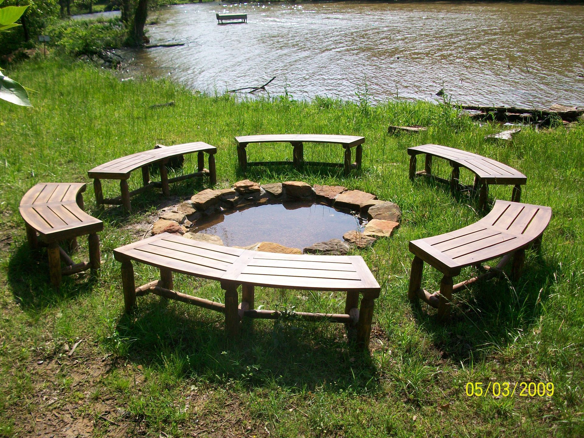 A group of benches around a fire pit with a river in the background