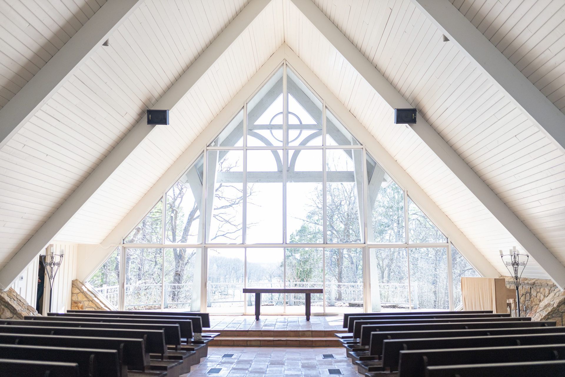 The inside of a church with rows of benches and a large window.