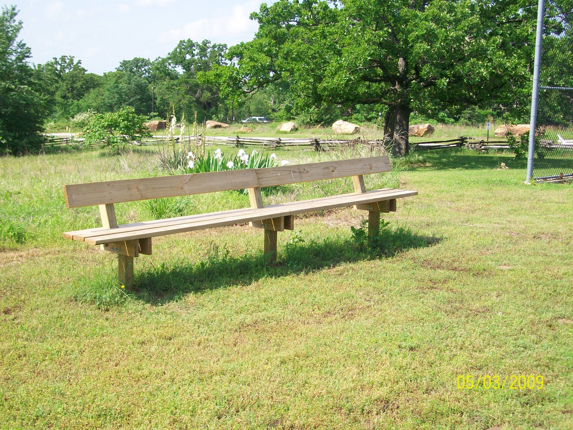 A wooden bench sits in the middle of a grassy field