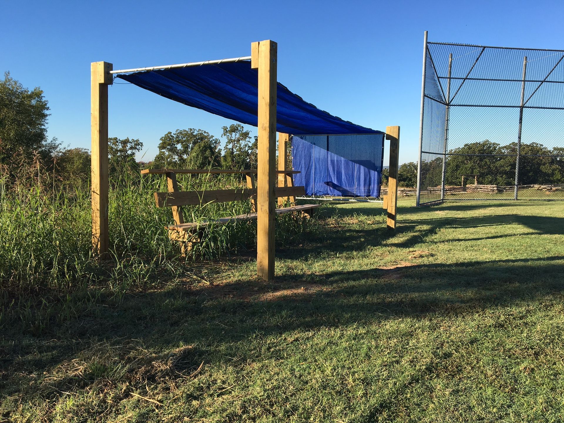 A blue tarp is hanging from a wooden post in a field.