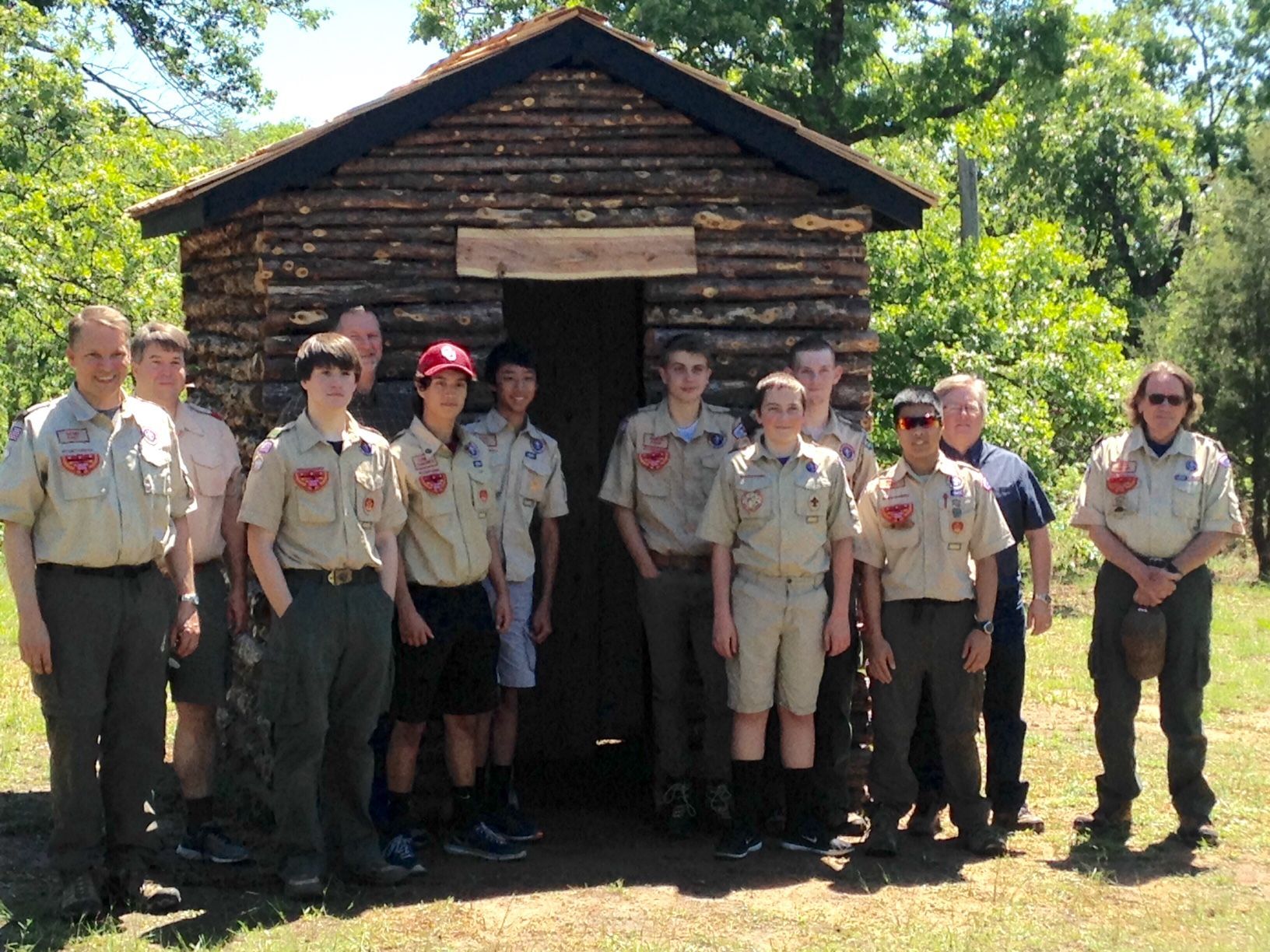 A group of people standing in front of a log cabin