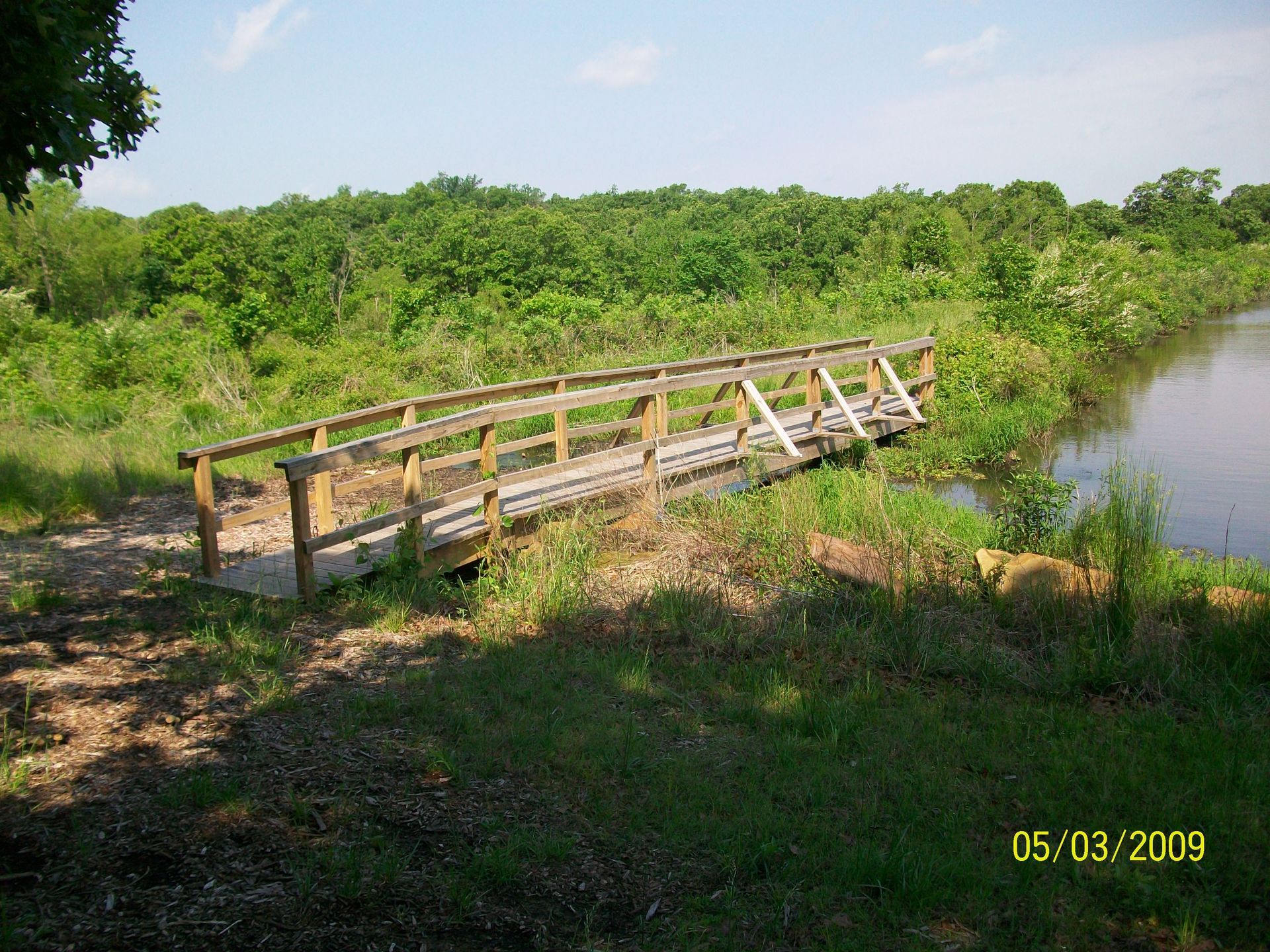 A wooden bridge over a river with trees in the background