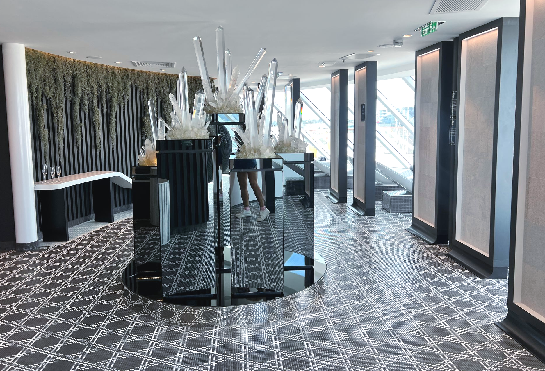 Modern wellness spa and thermal suite with large windows, quartz crystals, patterned floors, and decorative plants.