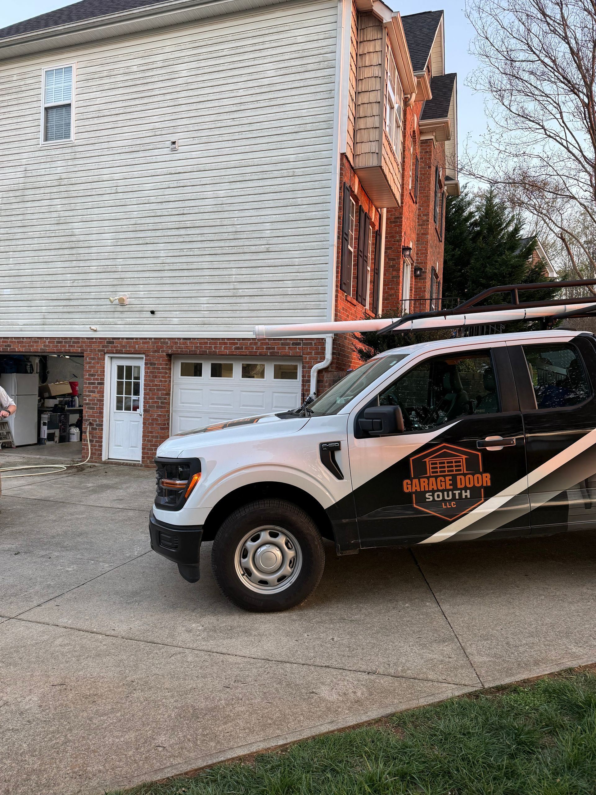 White service truck parked beside a damaged building with exposed orange framing and warped siding.