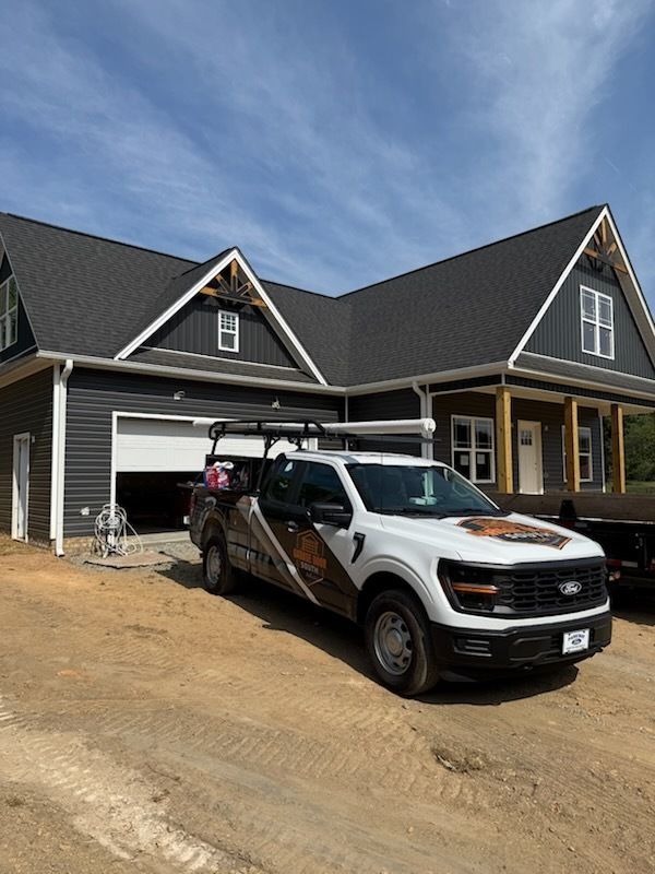 White pickup truck parked in front of a gray house with a garage under construction.