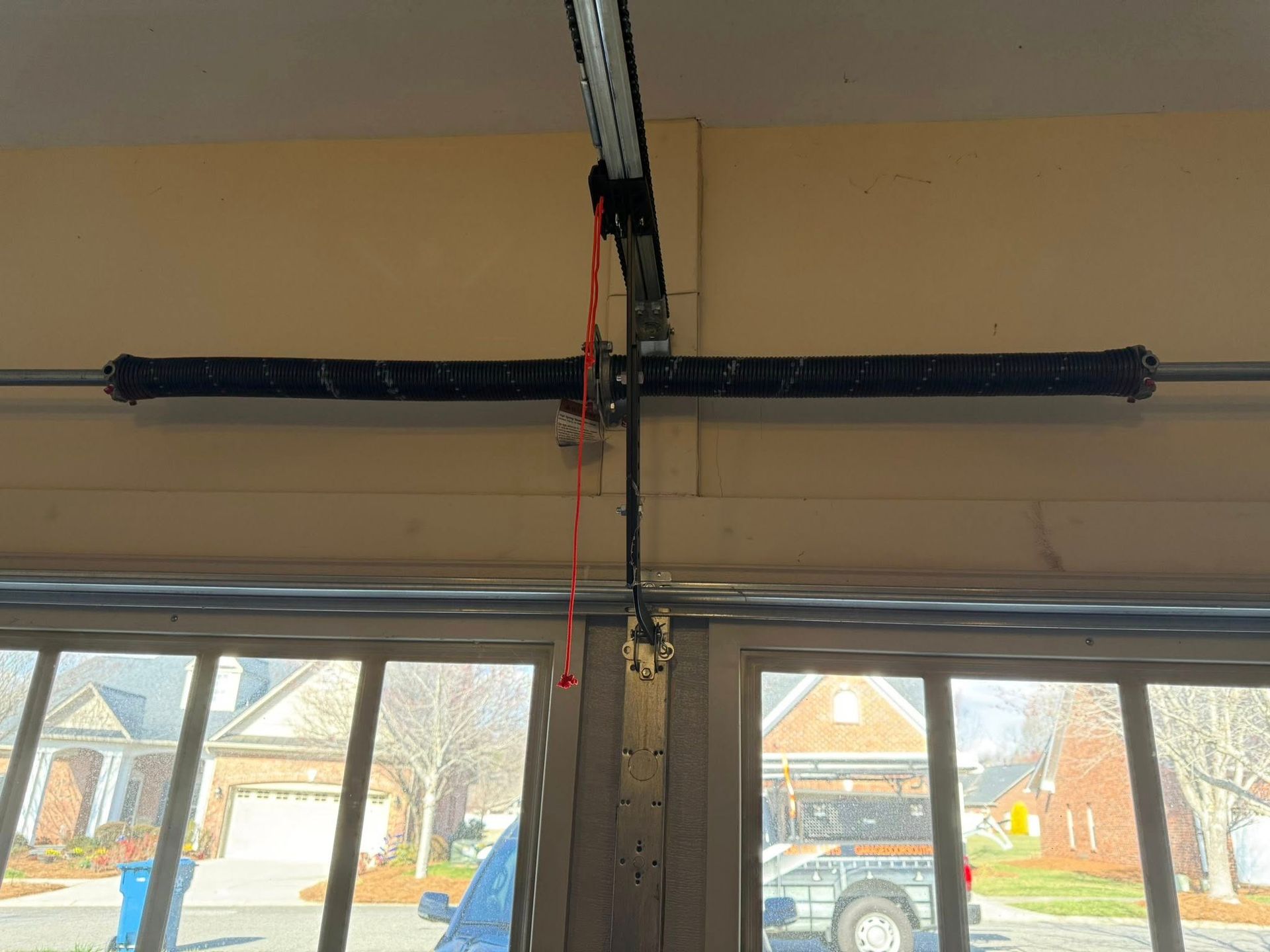 Garage door opener mechanism mounted above windows with a red cord hanging down