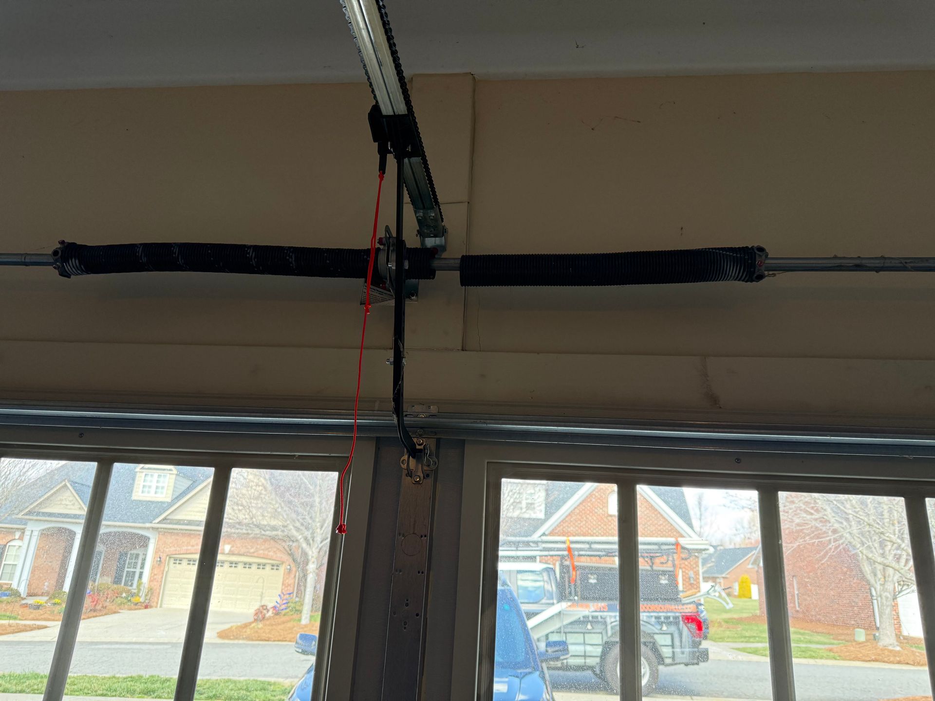 Coiled ventilation duct hanging from a concrete garage ceiling beside a garage door