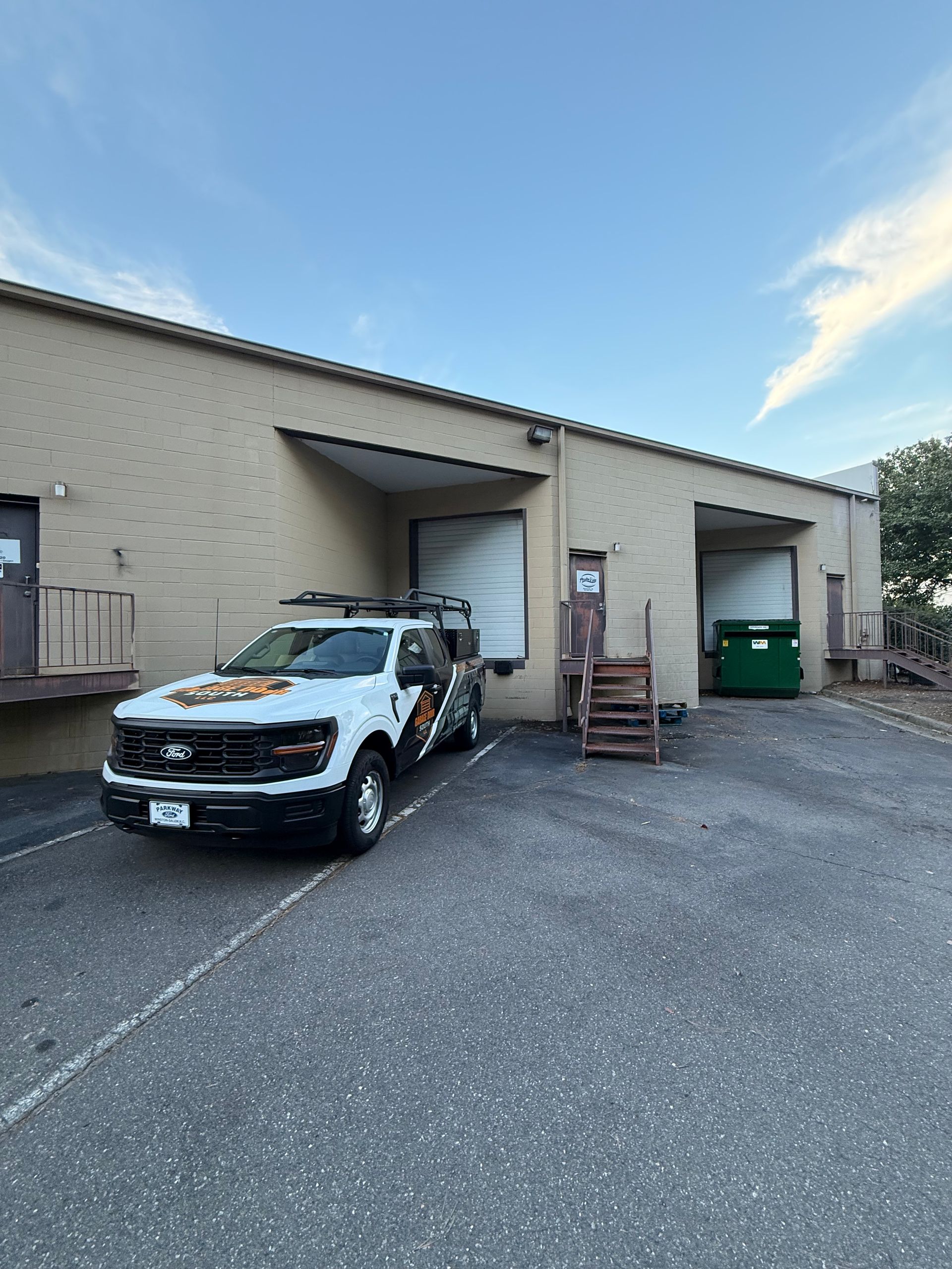 Row of modern industrial warehouse units with bright yellow loading doors and gray metal siding