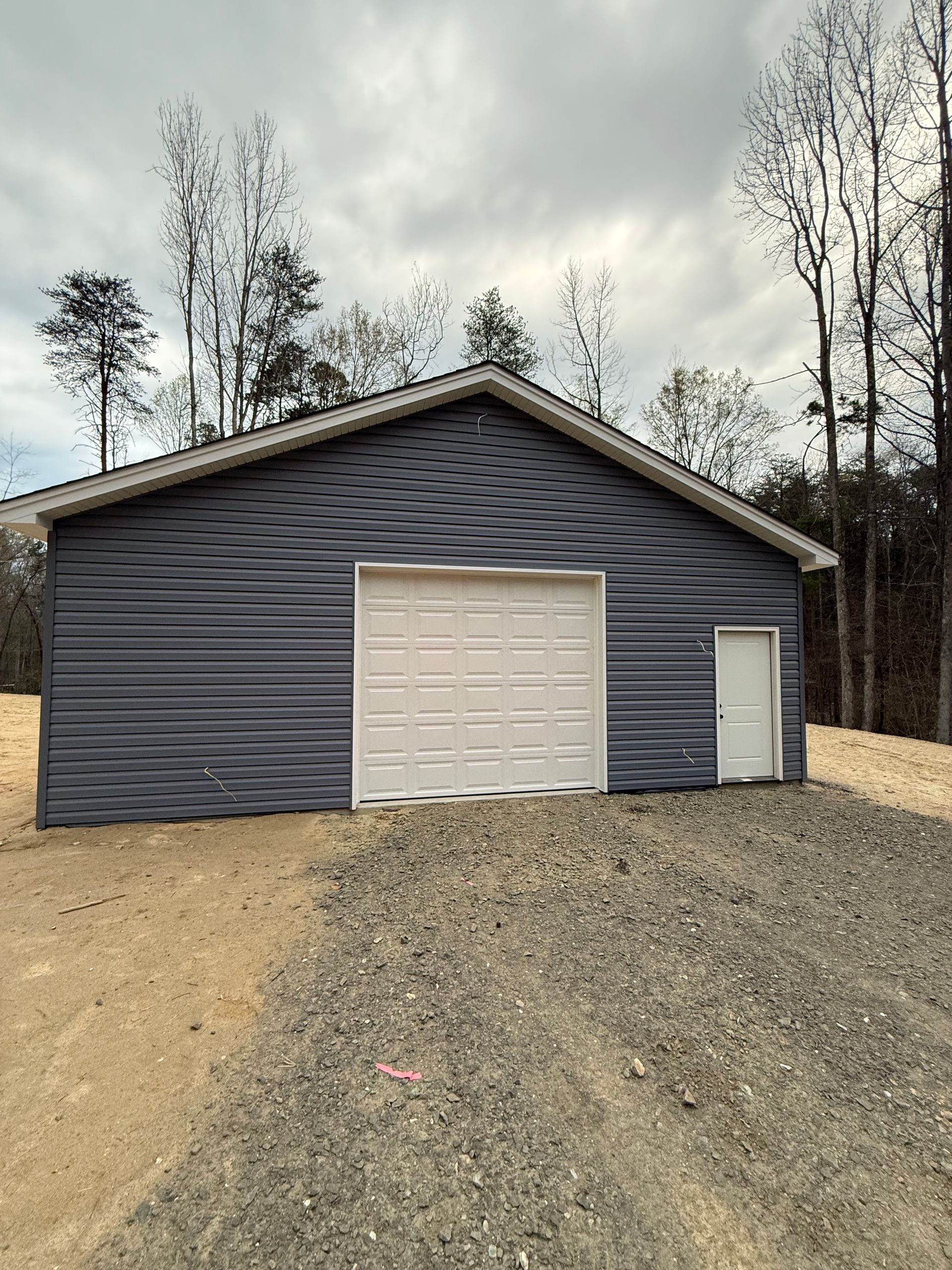 Modern white house exterior with two dark garage doors and shrubs in front