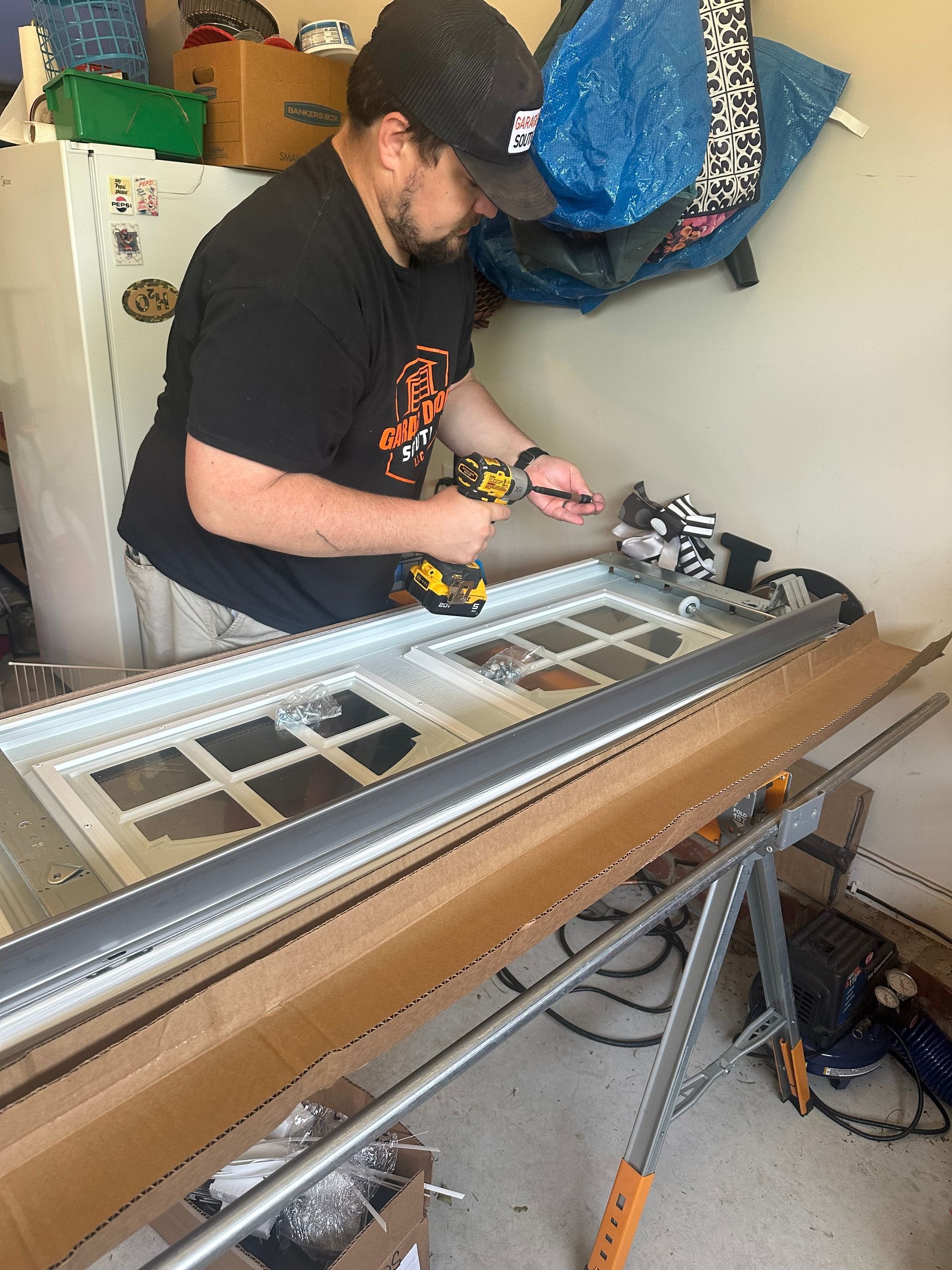 Technician on a ladder adjusting a ceiling-mounted garage door opener indoors