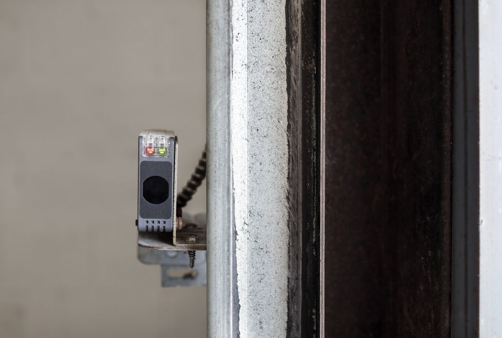 Small wall-mounted device with indicator lights beside a door frame and dark doorway
