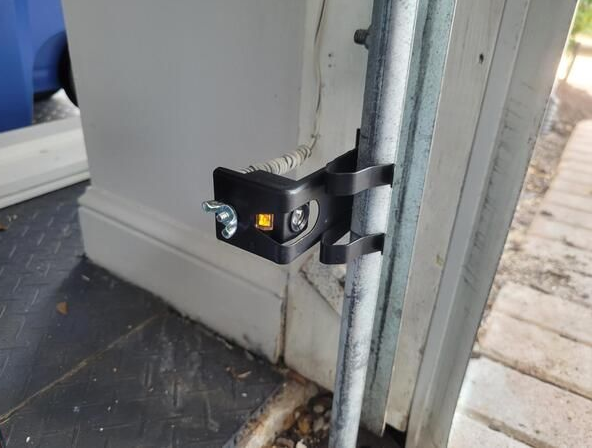 Black door latch securing a white door to a metal frame inside a bus or trailer