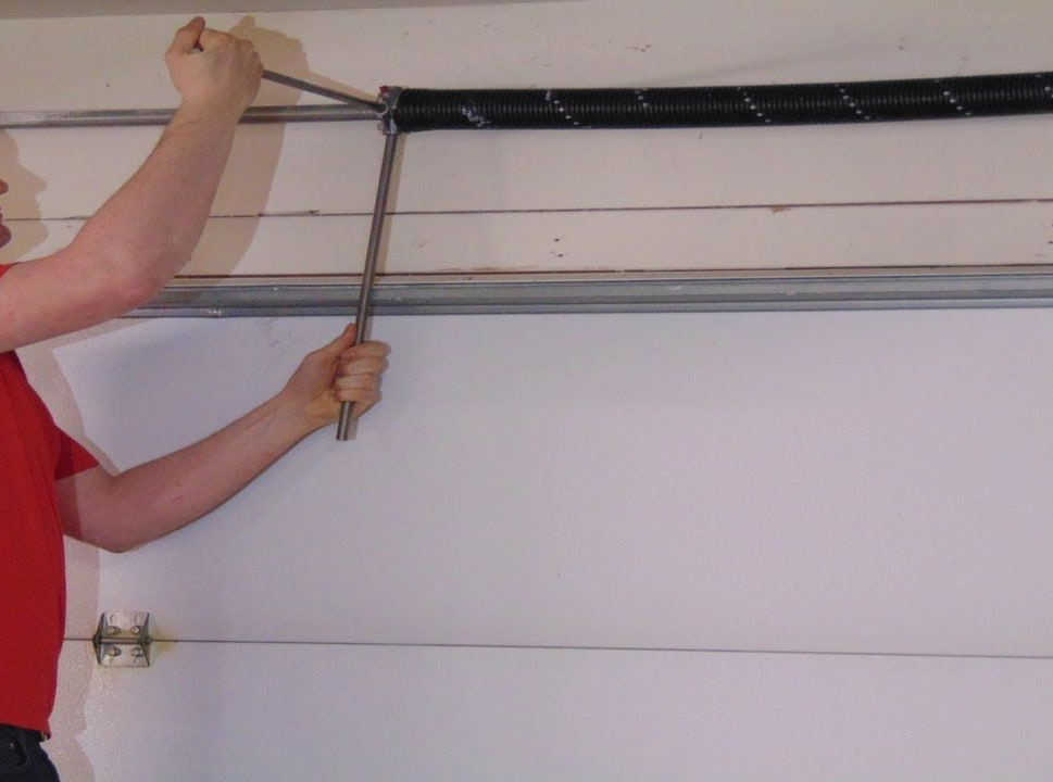 Person using a tool to adjust a garage door track and cable system
