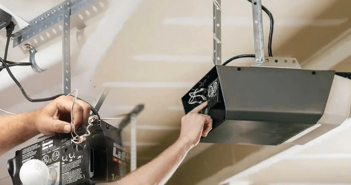 Hands adjusting a black garage door opener on a ceiling-mounted track