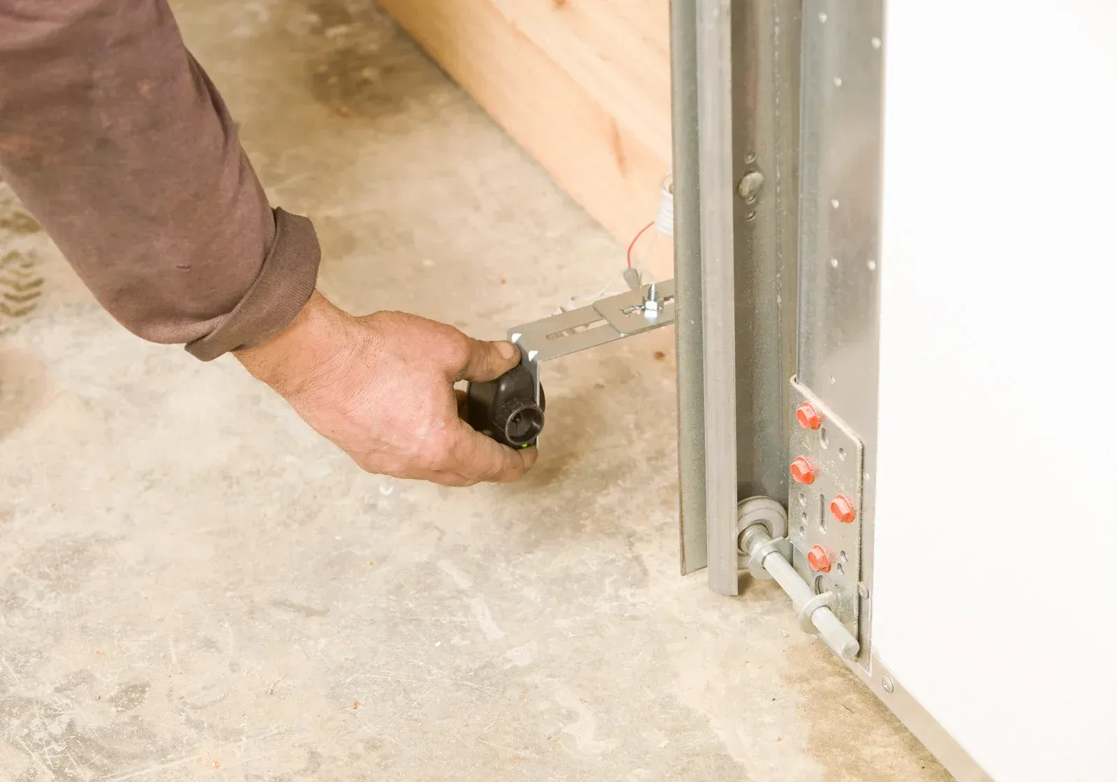 Hand using a tape measure to check a metal door frame on a concrete floor