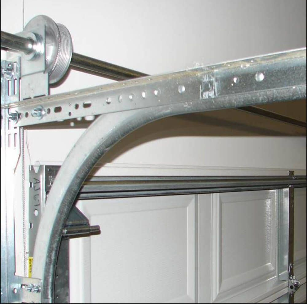 Garage door track and curved metal rail with overhead opener hardware close-up
