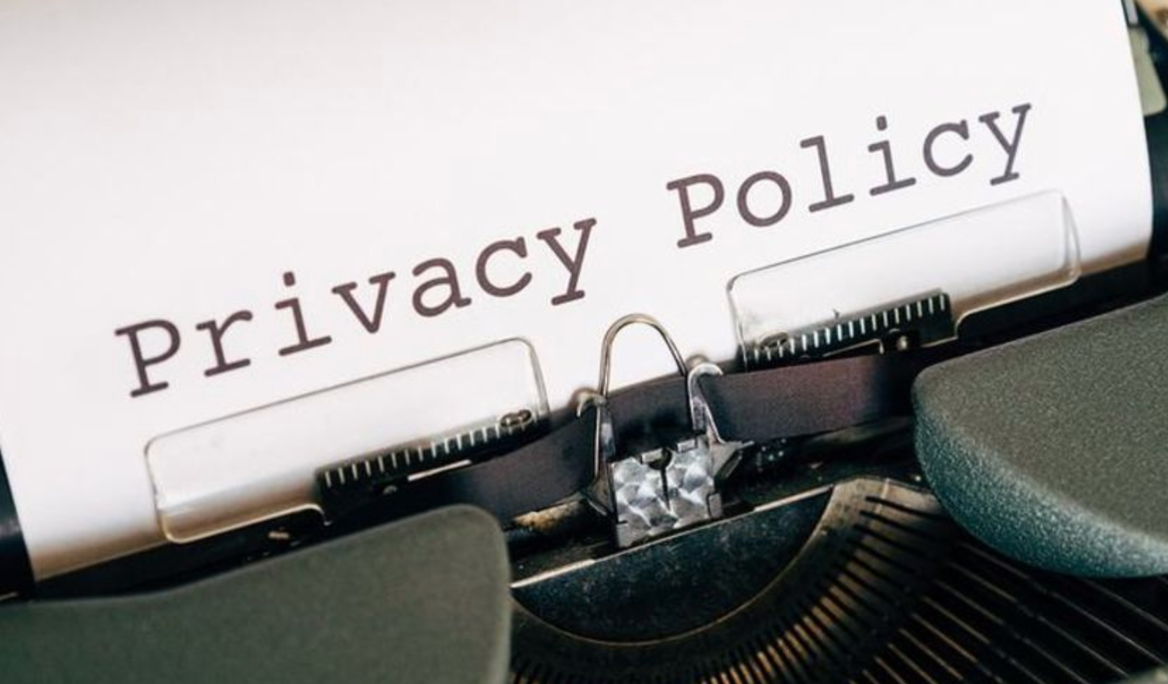 Typed “Privacy Policy” on paper in a typewriter, with the keys and platen visible.