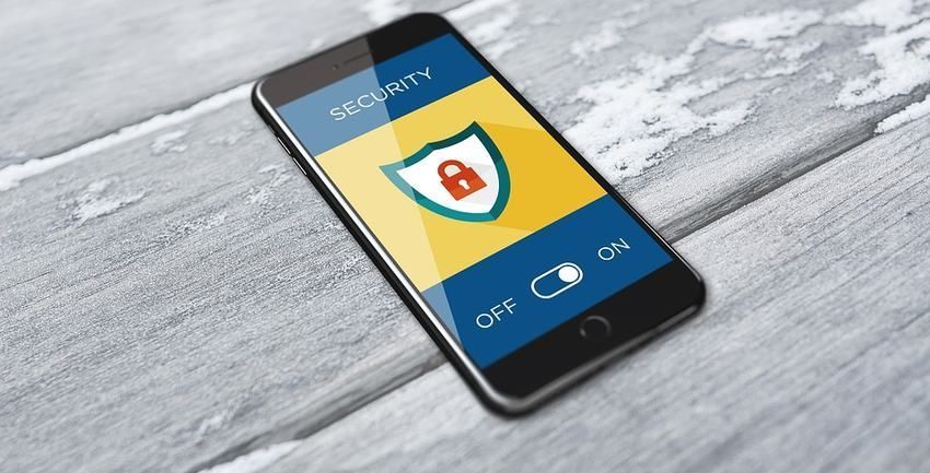 Smartphone displaying a security app screen with a shield icon on a wooden surface