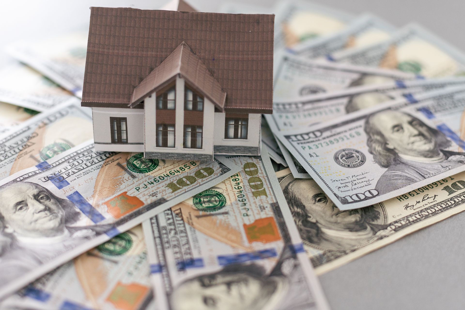 Toy house on top of a stack of $100 bills.