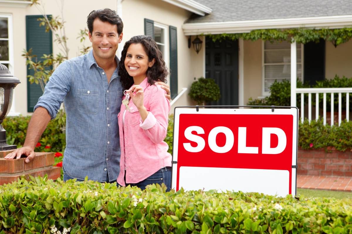 A happy couple standing near a sold sign near Lexington, Kentucky (KY)