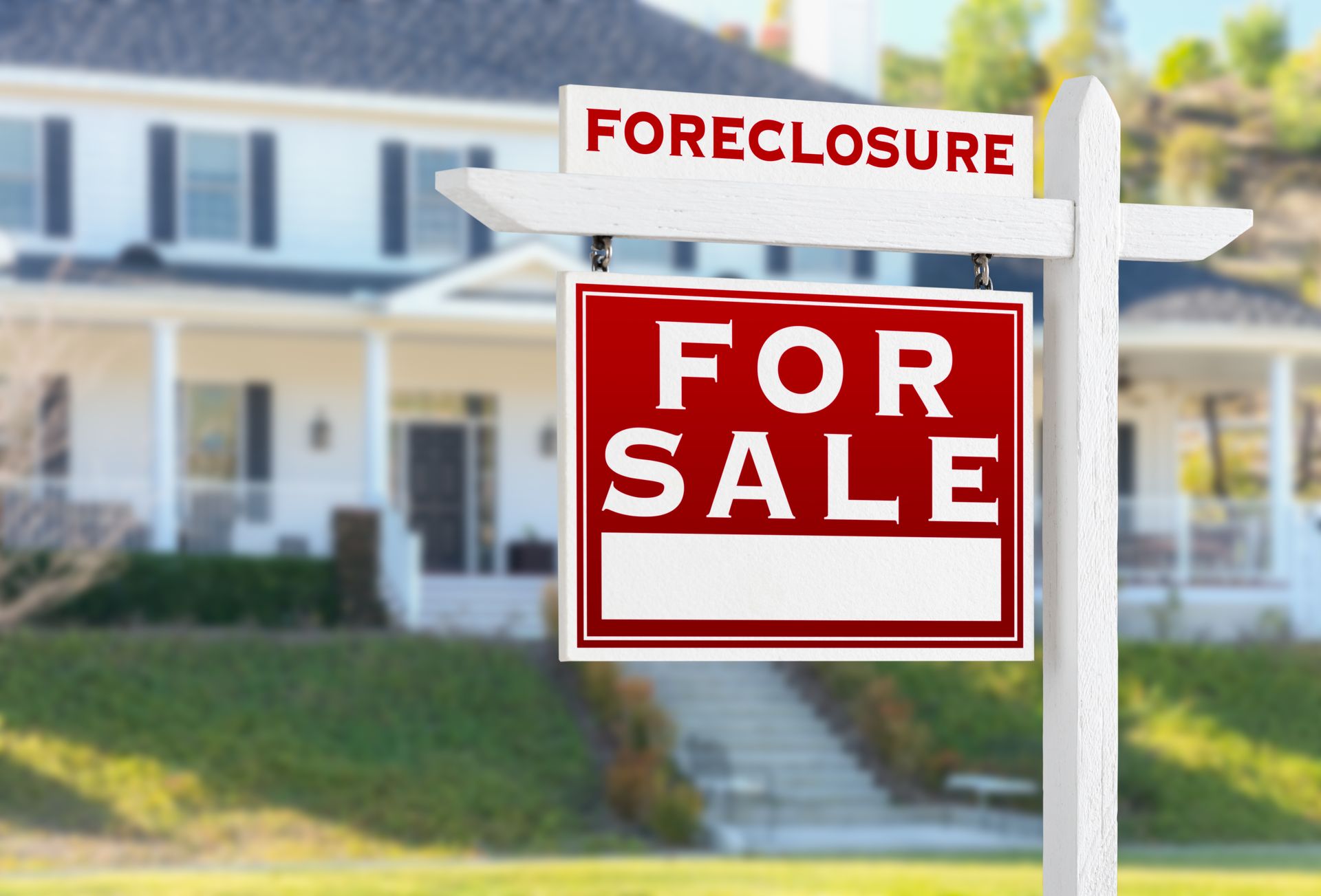 White home with a foreclosure sign in the front yard.