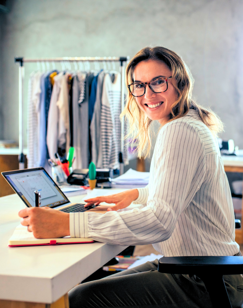 Uma mulher está sentada em uma mesa usando um laptop.