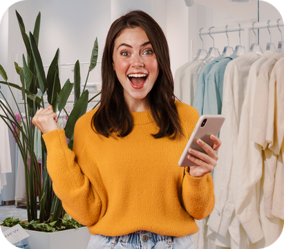 Uma mulher com um suéter amarelo está segurando um celular.