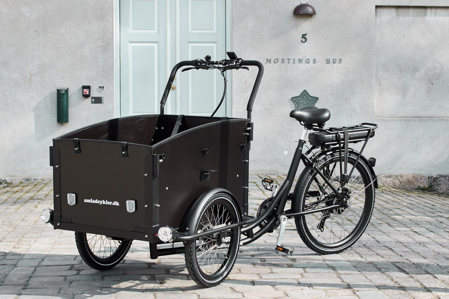Sort ladcykel parkeret uden for en bygning med nummer 5 over døren.