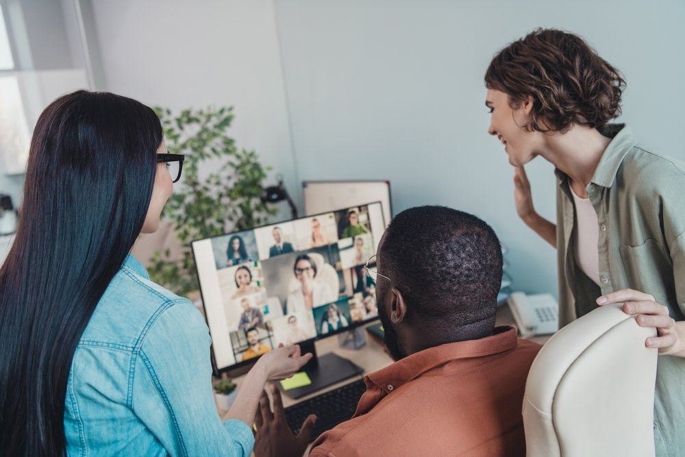 Two women and one man on a zoom call with co-workers