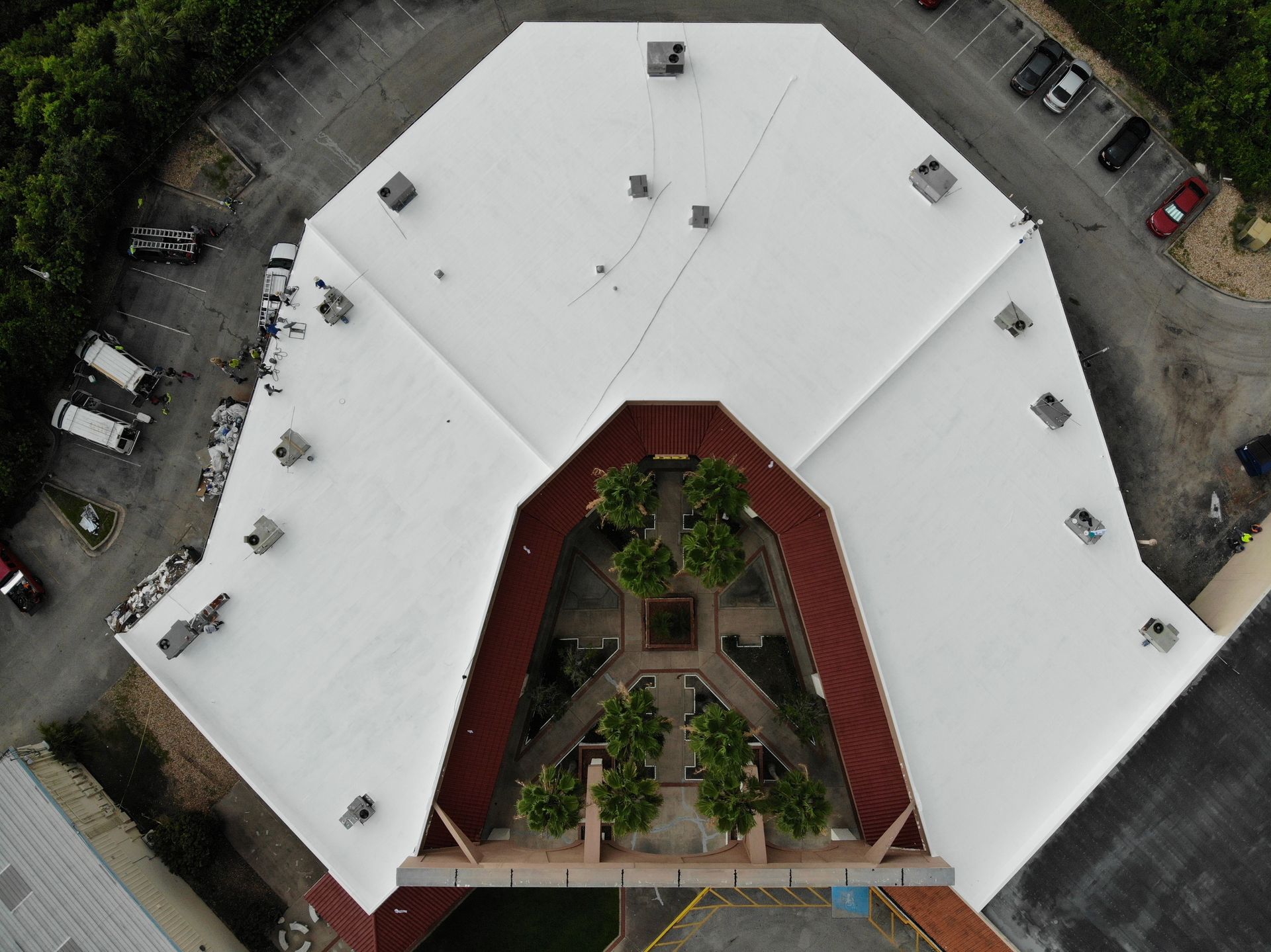 Flat commercial roof over an active Central Florida retail center with storefronts, rooftop units, and parking below