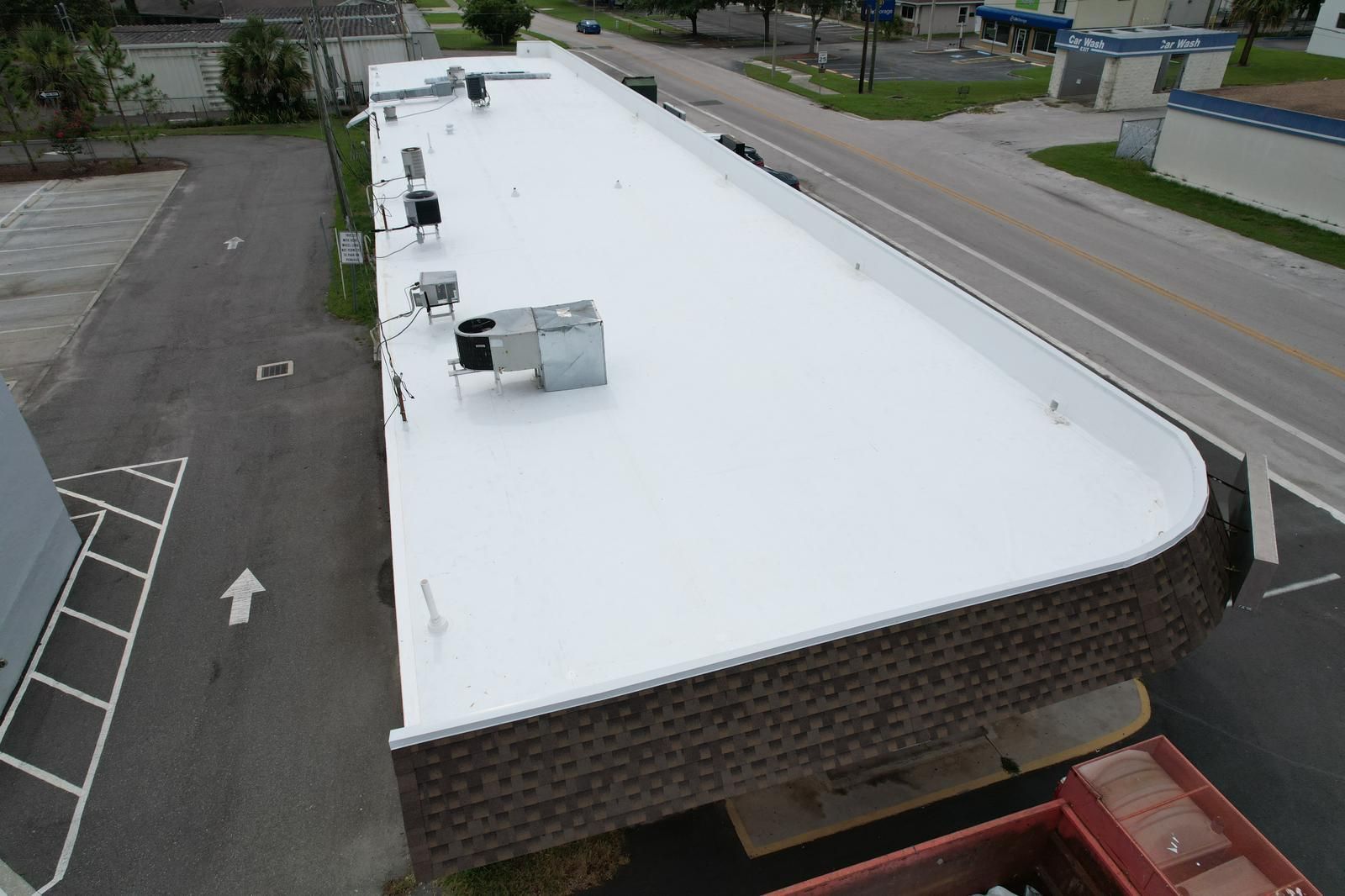 Aerial view of a white commercial low-slope roof beside a roadway